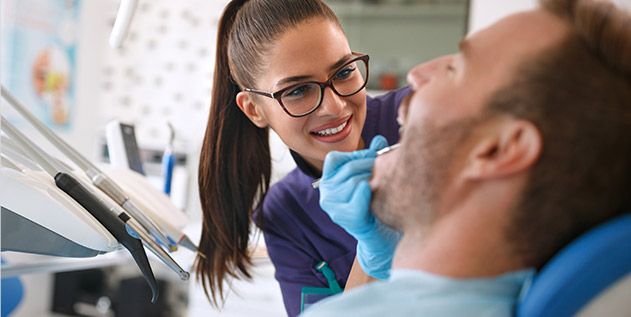 Dental team member performing a dental exam on a patient
