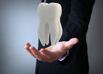 Man holding a tooth for dental insurance in Crown Point