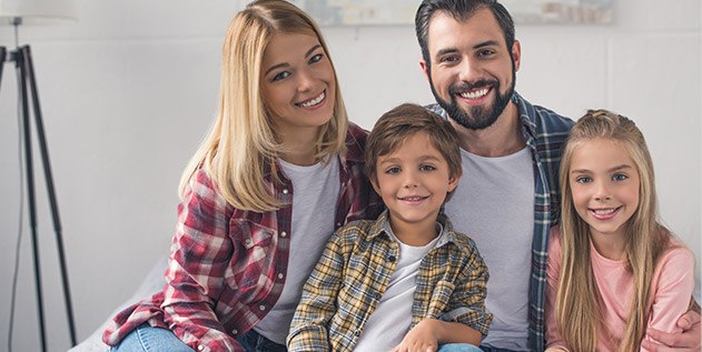 Mother father and two children smiling outdoors