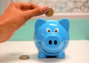 Hand putting coin in blue piggy bank