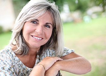 gray-haired woman smiling with dental implants in Crown Point