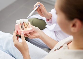 dentist showing a patient a model of how dental implants work