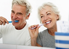 older couple brushing teeth in bathroom 