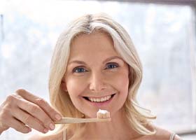 Woman brushing teeth in Crown Point