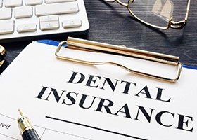 an empty dental insurance claim form attached to a clipboard with a pen sitting next to it