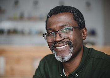 a person wearing glasses and smiling after tooth replacement with dental implants