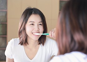 woman brushing for dental implant post-op instructions in Crown Point