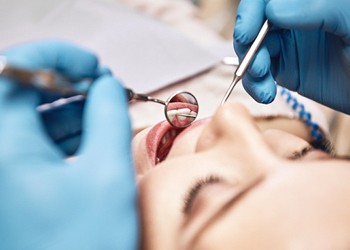 A female patient undergoing a dental checkup and cleaning to prevent dental emergencies