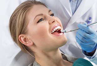 Woman receiving dental exam and teeth cleaning during preventive dentistry visit