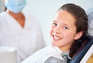 Young girl smiling in dental chair after fluoride treatment