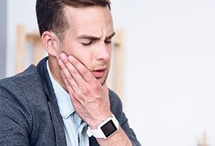 Man holding jaw in pain before T M J therapy