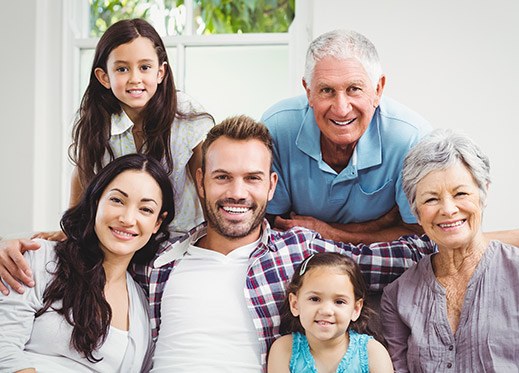 Three generations of family members smiling together after family dentistry visit