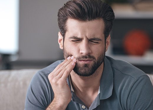 Man holding jaw in pain before emergency dentistry