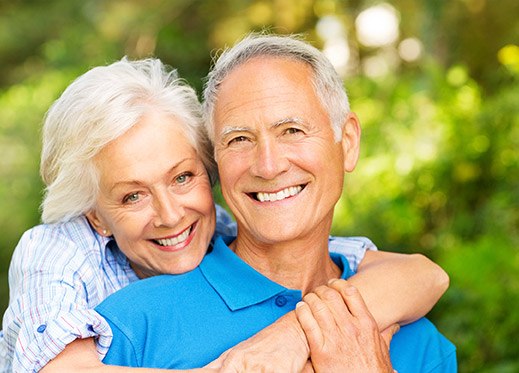 Smiling older man and woman outdoors after restorative dentistry