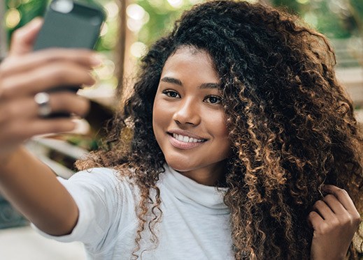 Smiling young woman taking selfie after cosmetic dentistry