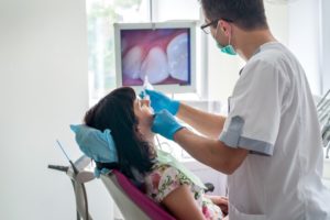 dentist using an intraoral camera to show a patient their teeth 