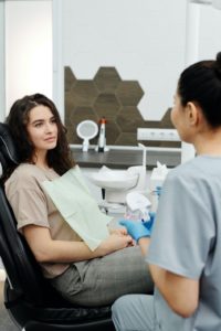 Dentist explaining TMJ pain to woman in chair