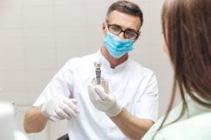 Dentist holding dental implant for full mouth reconstruction