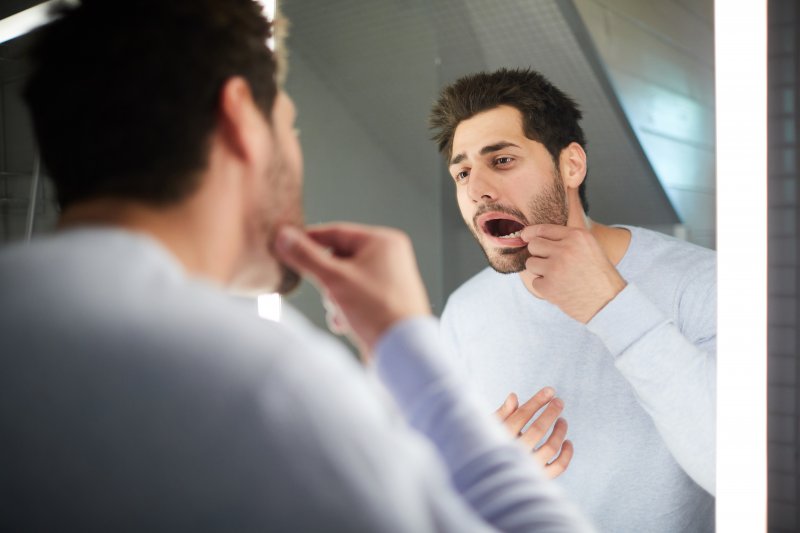person looking at their tooth in the mirror