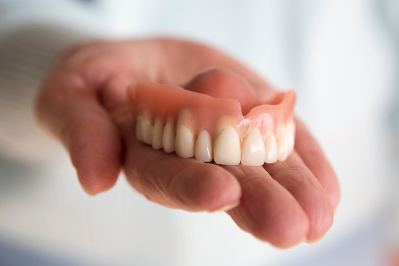 A hand holding a removable denture