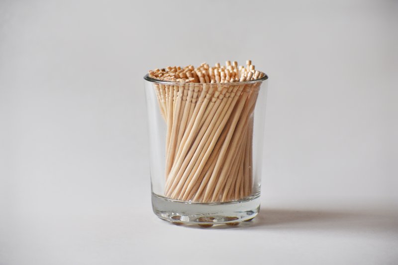 A clear glass filled with toothpicks
