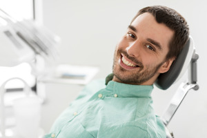 Bearded male dental patient sitting back in chair and smiling