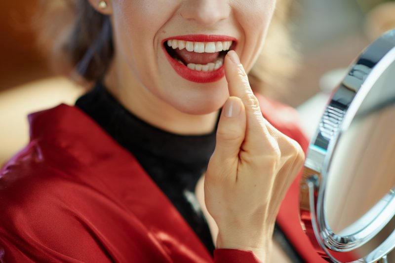 Woman looking at her veneers in a mirror