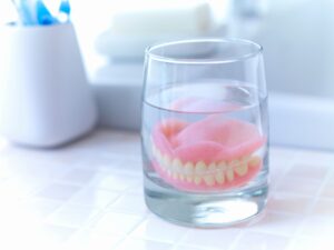 Dentures in a glass of water on bathroom counter