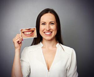 Woman with white teeth holding before picture.